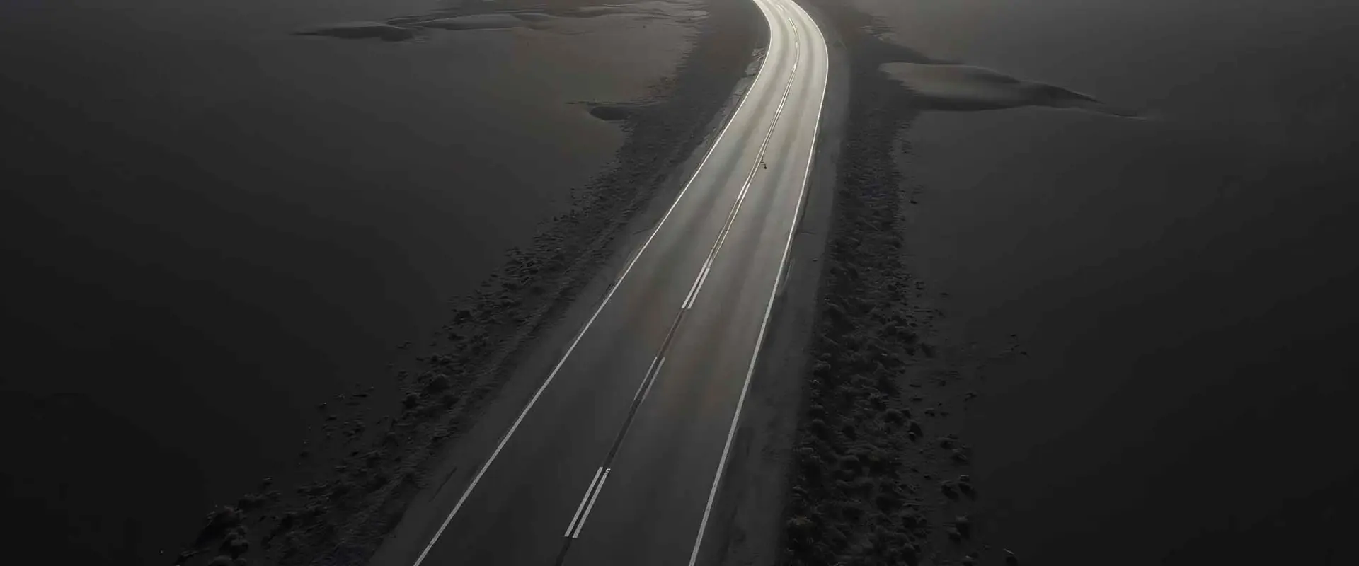 A lonely road stretching through a vast black desert.